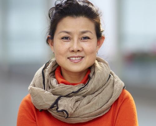 Asian woman outside wearing a pretty scarf smiling at the camera